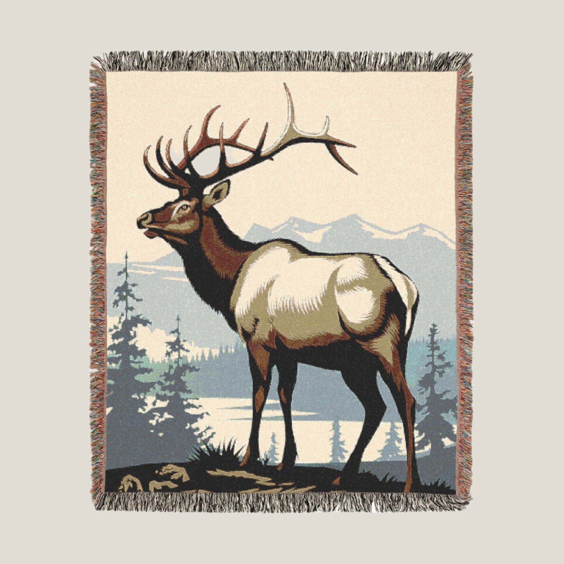 Majestic elk standing on a hilltop with mountains and a lake in the background, featured on a woven throw blanket.